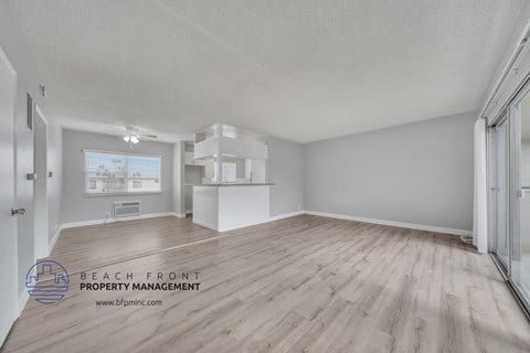 a spacious living room with hardwood flooring and a kitchen
