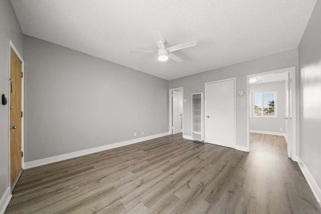 an empty living room with hardwood floors and a ceiling fan