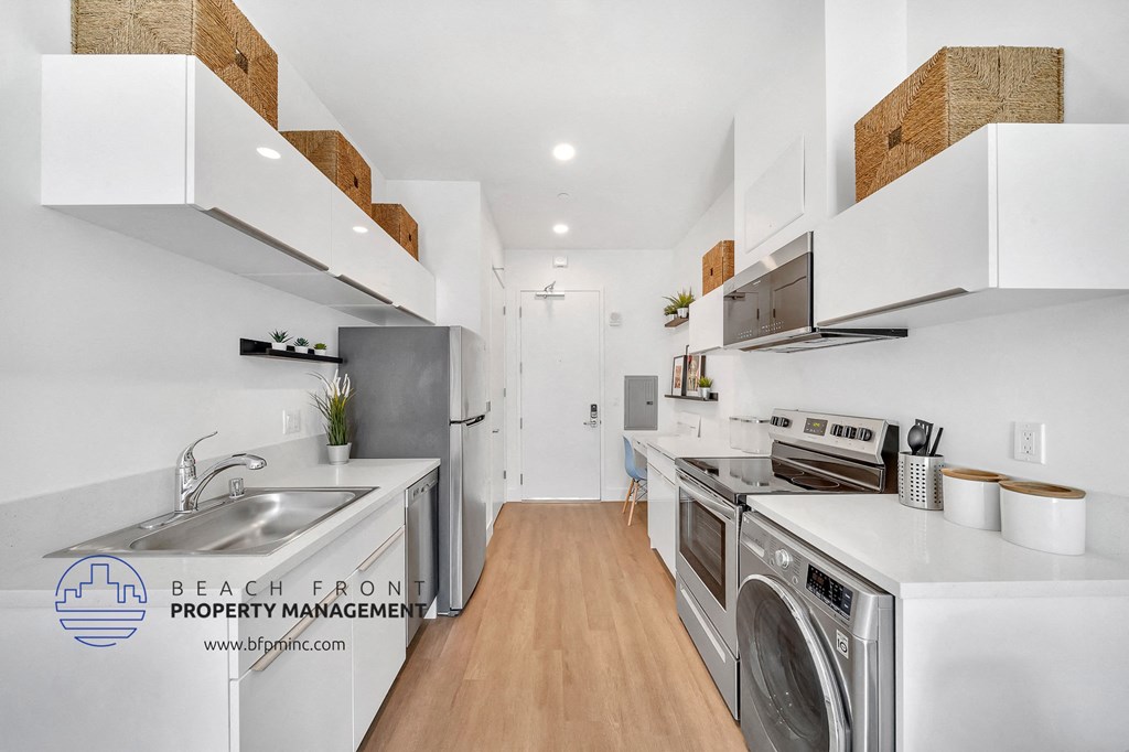a white kitchen with stainless steel appliances and a washer and dryer