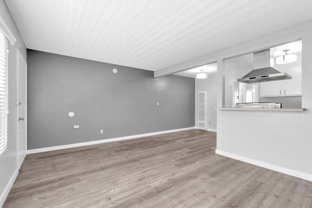 the living room and kitchen in a new home with grey walls and wood flooring