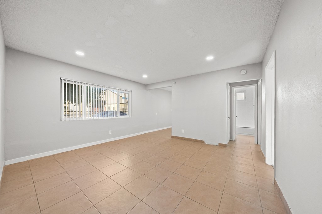 the living room and entryway of a house with white walls and tiled floors
