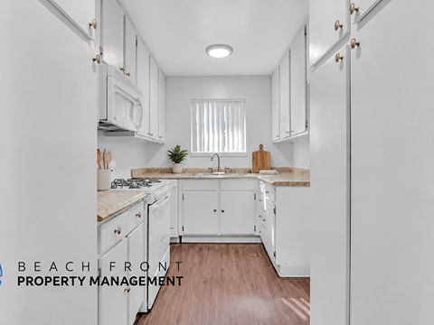 A kitchen with white cabinets and a wooden floor.