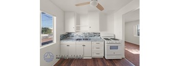 A kitchen with white cabinets and a marble countertop.