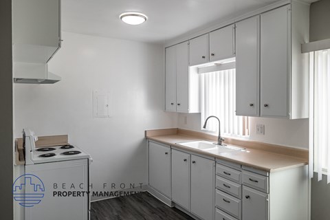 A kitchen with white cabinets and a stove top oven.