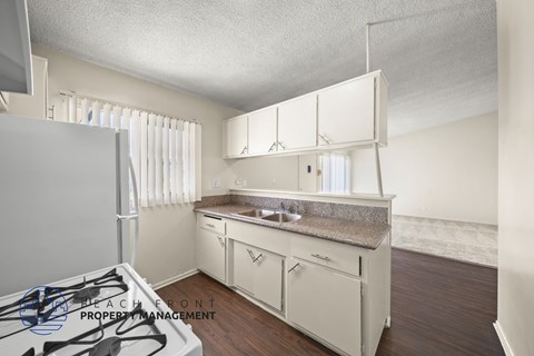 A kitchen with a stove top oven and white cabinets.