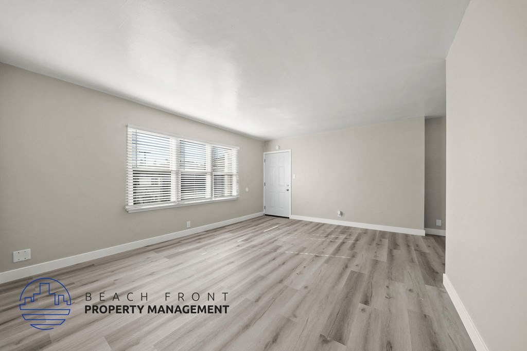 A room with wooden flooring and a window with blinds.