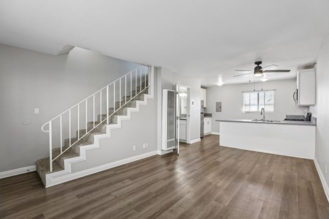 A spacious room with a staircase and a kitchen area.