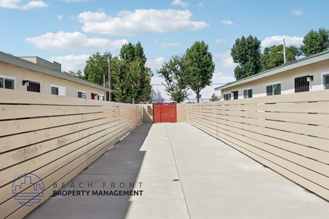 A long concrete walkway with a red door at the end.