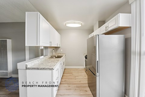 A kitchen with white cabinets and a refrigerator.