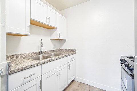 A kitchen with white cabinets and a granite countertop.