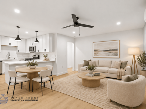 A well-lit, modern living room with a dining area and kitchen in the background.