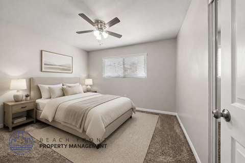 A well-lit bedroom with a large bed and a ceiling fan.
