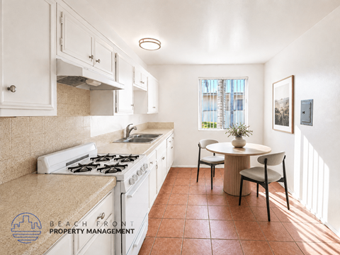 A kitchen with a stove top oven and a dining table with chairs.