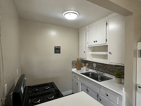 A small kitchen with a black stove top and white cabinets.