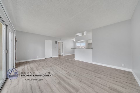 a spacious living room with white walls and wood flooring
