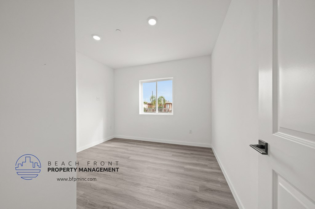 a living room with white walls and wood flooring and a window