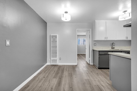 the kitchen and living room of a renovated apartment with white cabinets and wood flooring