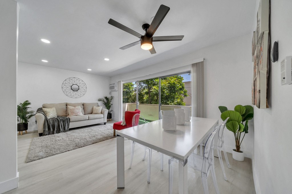 a white dining room with a white table and a ceiling fan