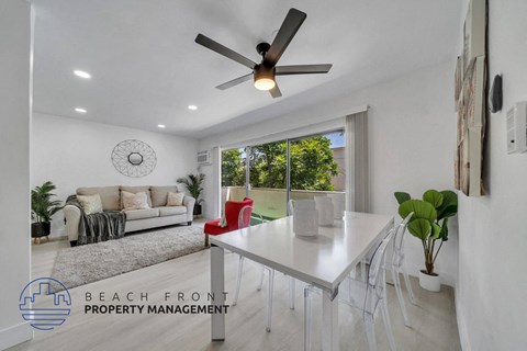 a white dining room with a white table and a ceiling fan