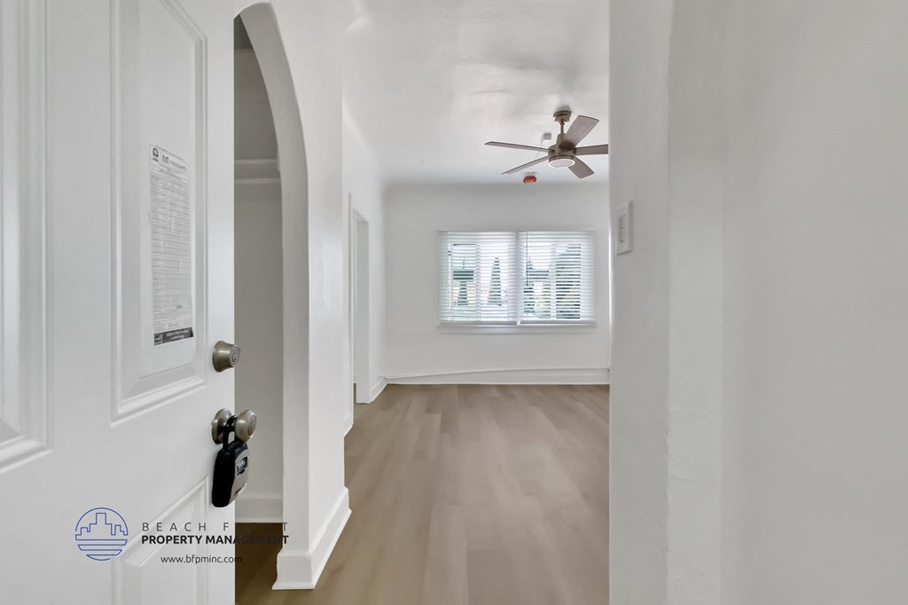 a living room with white walls and a ceiling fan