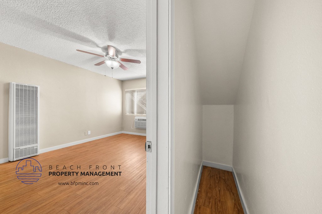 the living room and dining room of an apartment with wood floors and a ceiling fan