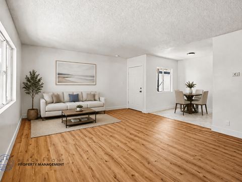 A living room with a white couch, a coffee table, and a painting on the wall.