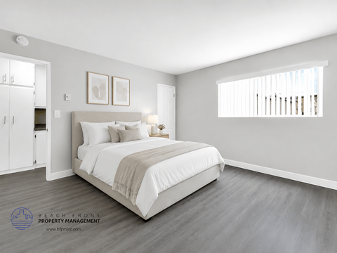 A bedroom with a large bed and a wooden floor.