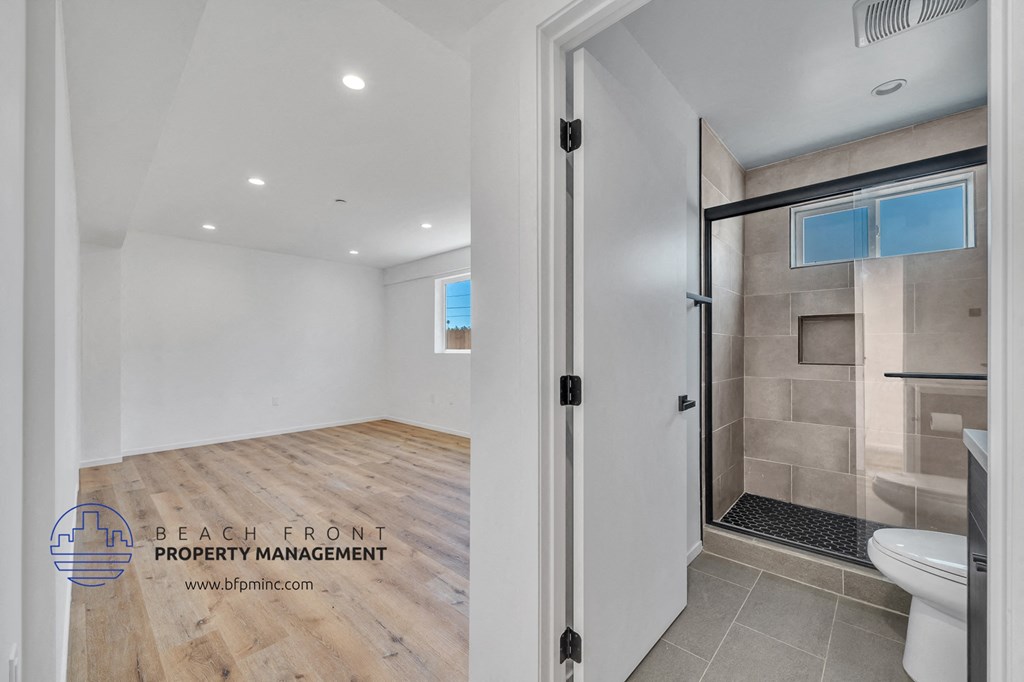 a bathroom with a shower and a toilet and a glass door