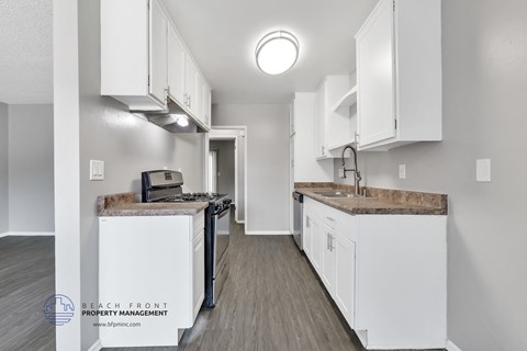 A kitchen with white cabinets and a wooden floor.