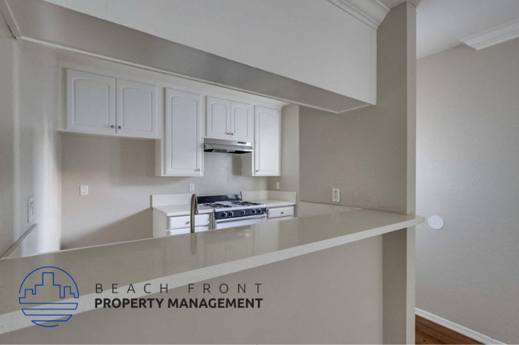 an empty kitchen with white cabinets and a counter top