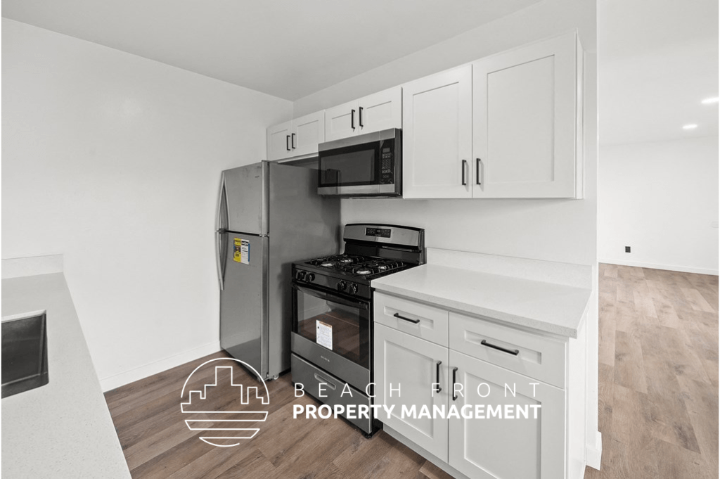 a white kitchen with white cabinets and a stainless steel refrigerator