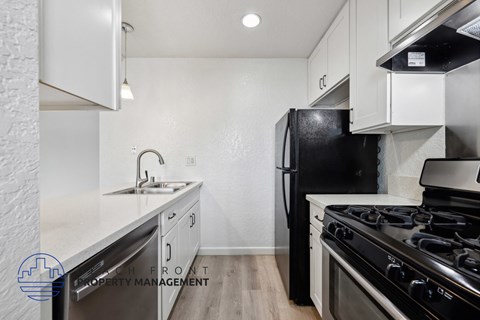 A kitchen with a black fridge and stove top oven.