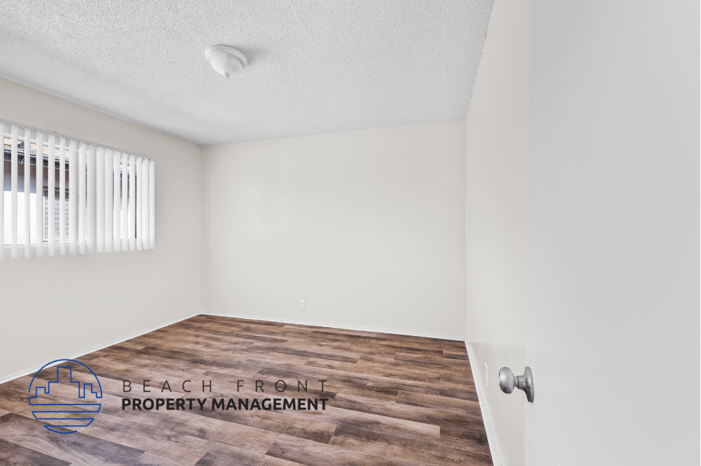 the living room of an apartment with wood flooring and a window