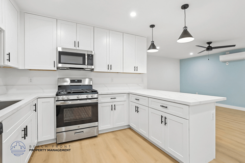 A kitchen with white cabinets and a stainless steel stove top oven.