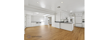 A spacious kitchen with white cabinets and wooden floors.