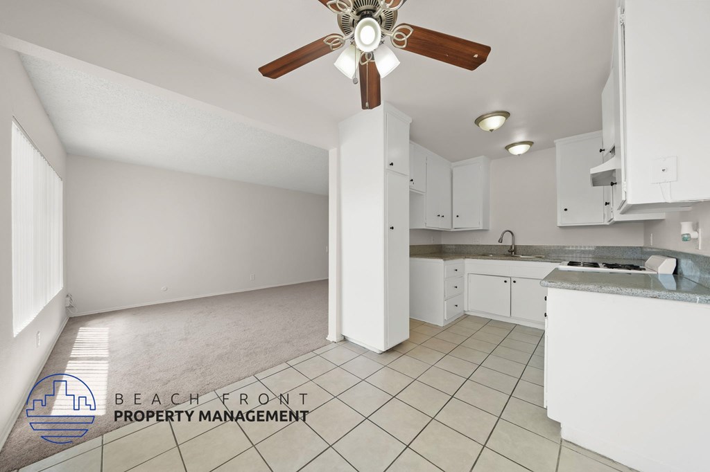 A kitchen with white cabinets and a ceiling fan.