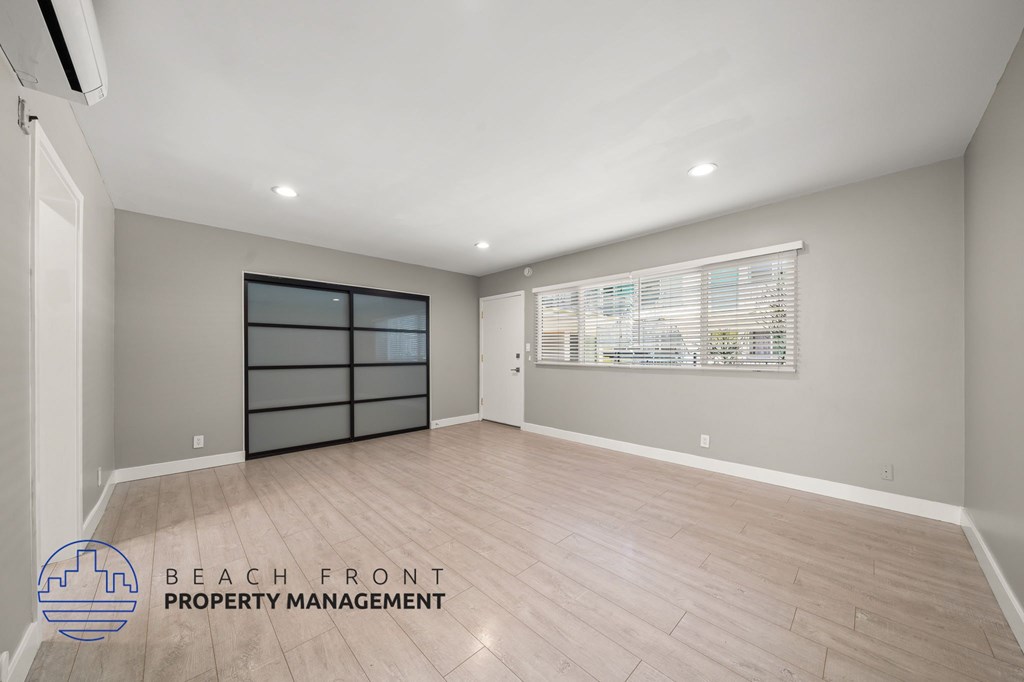 A spacious room with a sliding door and a window with blinds.