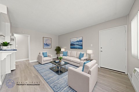 A living room with a white couch, a blue rug, and a painting on the wall.