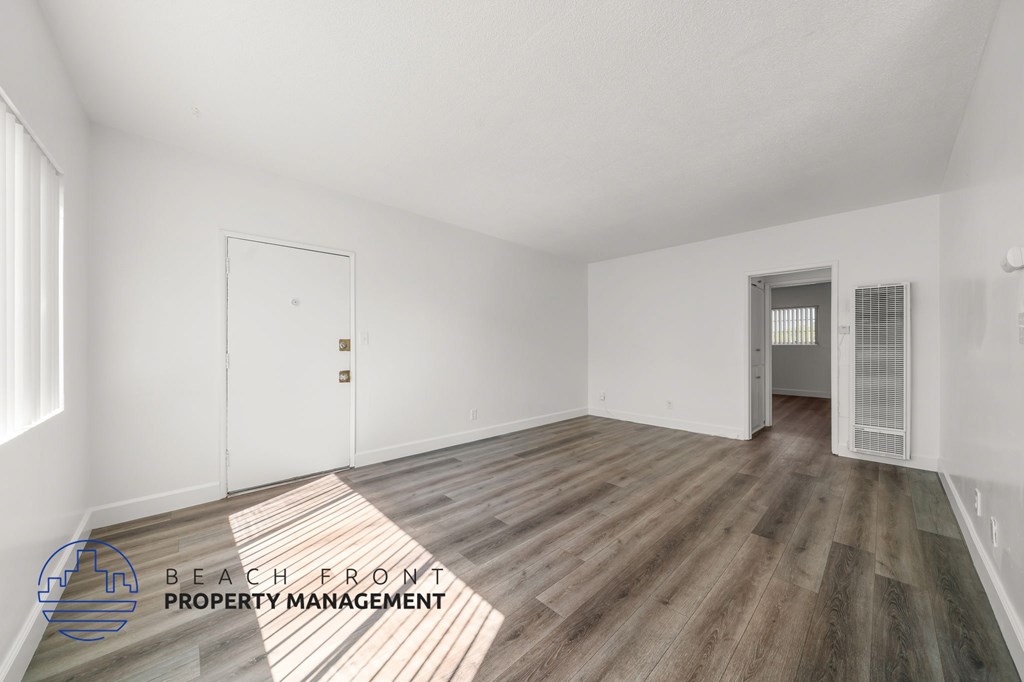 A room with wooden flooring and two doors, one of which is open.
