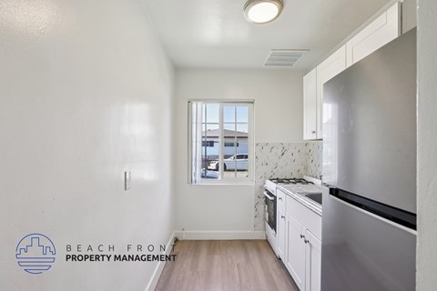 A kitchen with a stainless steel refrigerator and wooden floors.