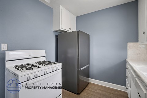 A kitchen with a stove, refrigerator, and cabinets.