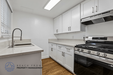 A kitchen with white cabinets and a stove top oven.