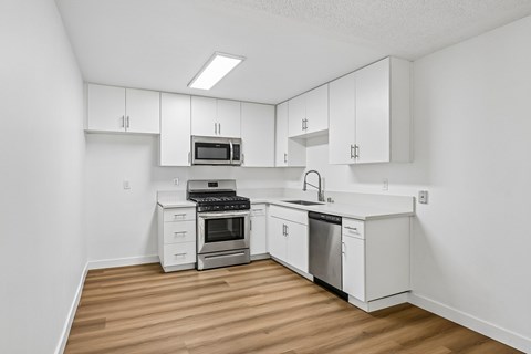 A kitchen with white cabinets and appliances.