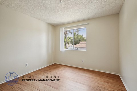 A room with a window showing a view of a building and trees outside.