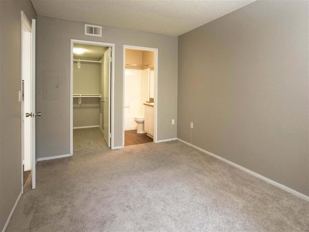 an empty living room with a door open to a bathroom