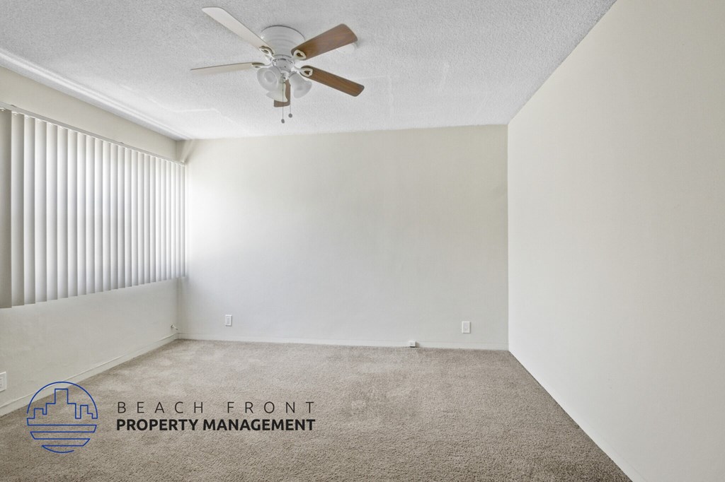A room with a carpet floor and a ceiling fan.
