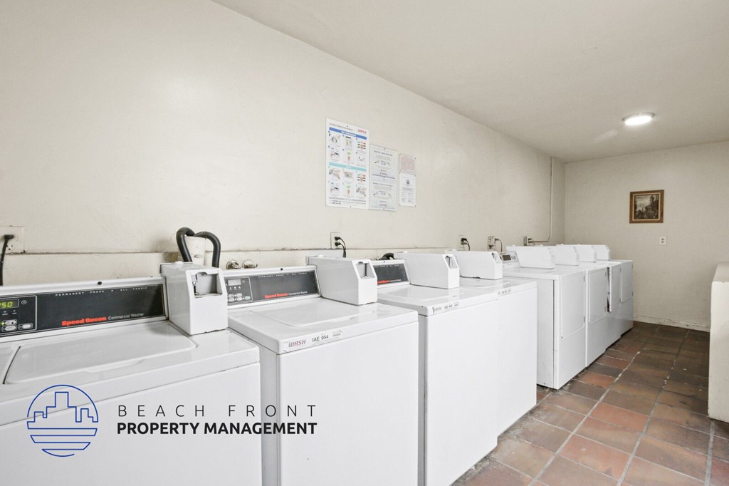 A laundry room with washers and dryers and a sign that says Beach Front Property Management.