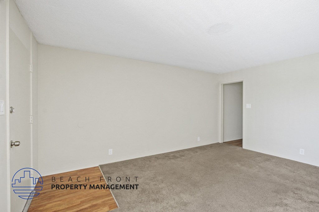 A room with a carpeted floor and a door on the right side.