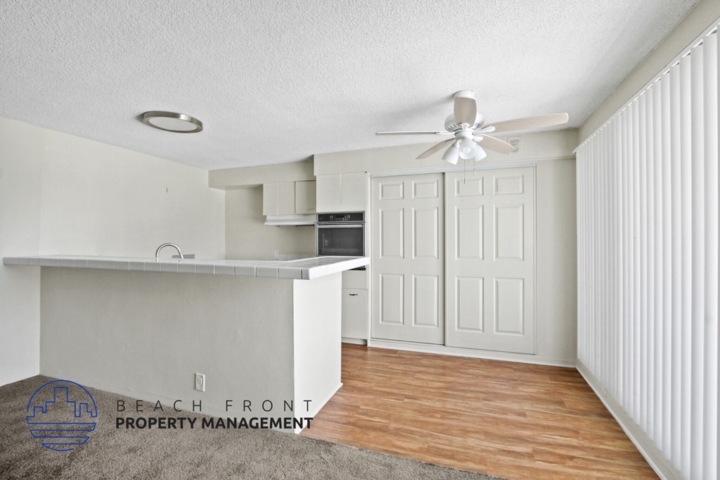 A room with a ceiling fan and a kitchenette.