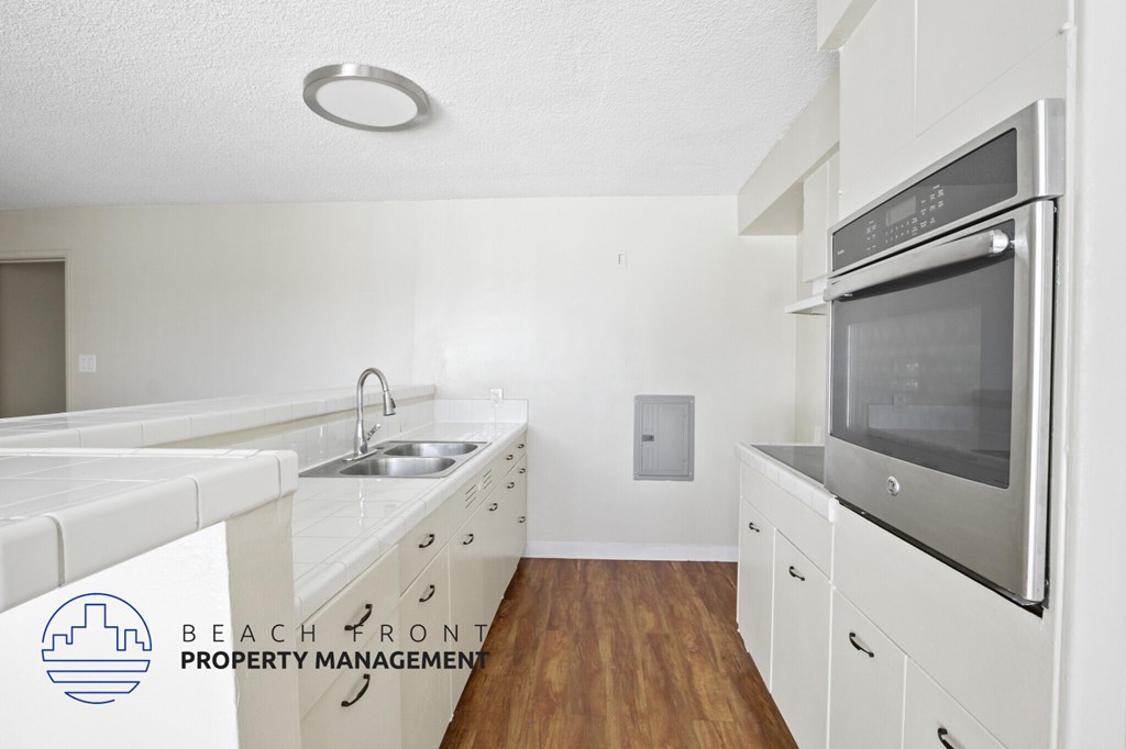 A kitchen with white appliances and wooden floors.